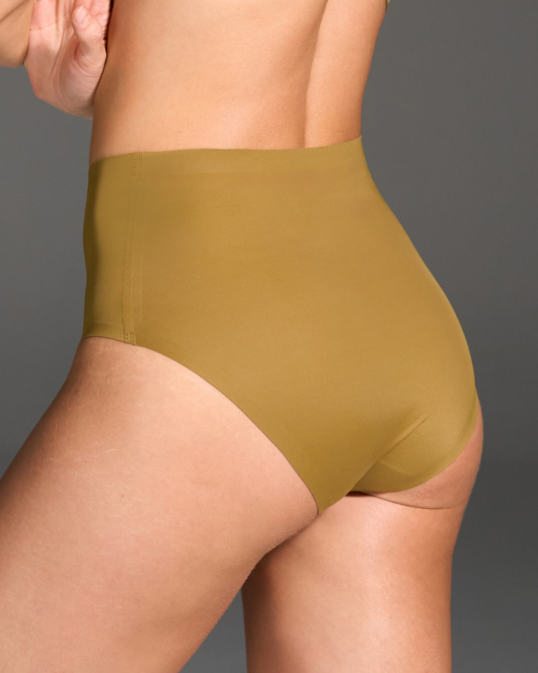 Person wearing butternut underwear against a gray background