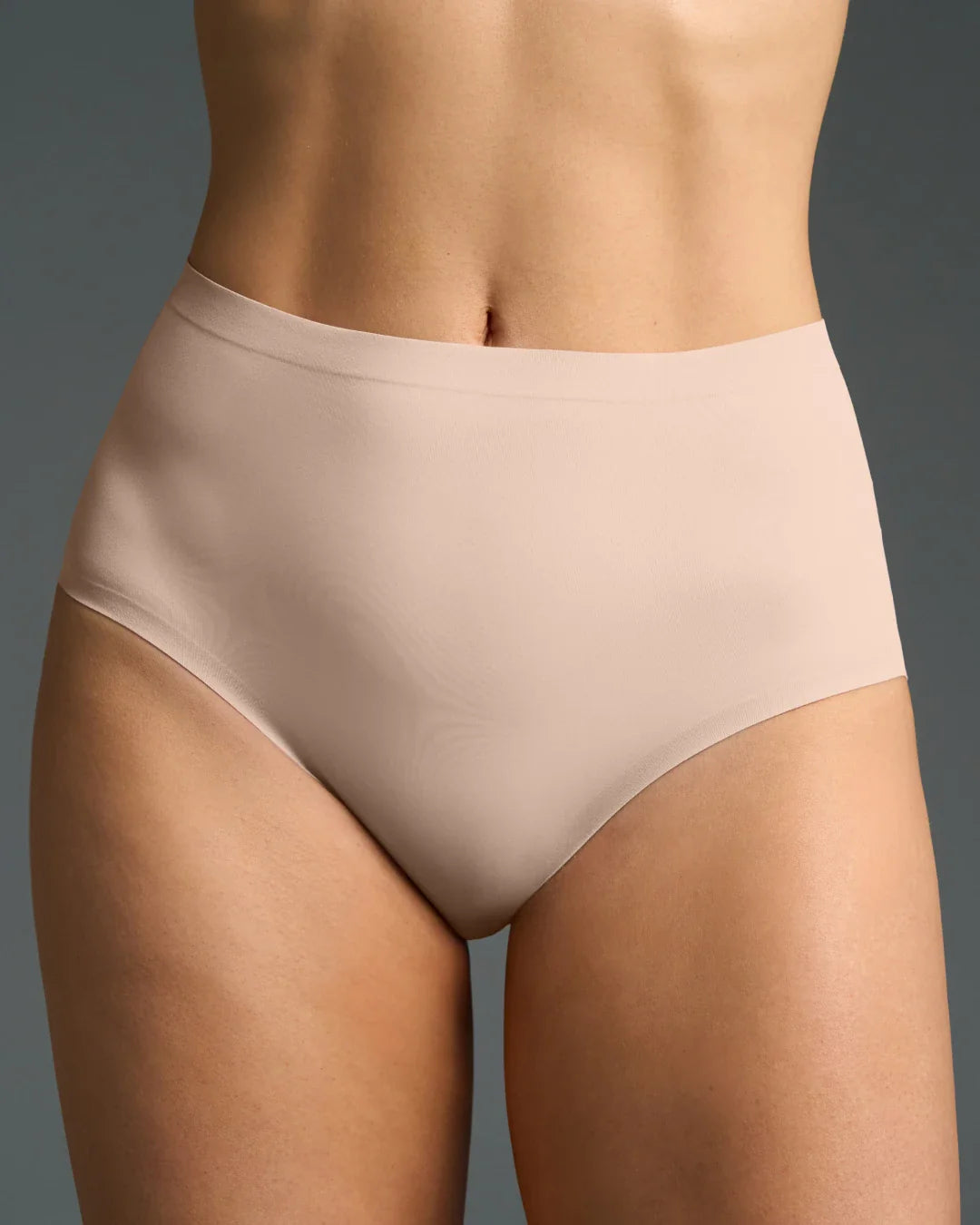 Seamless high rise panties in nude color worn by a model, offering smooth coverage and a flattering fit